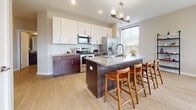 Located in Covington, Kentucky, this contemporary single-floor residence offers a well-designed open layout that seamlessly connects its living, dining, and kitchen areas. The kitchen is a standout feature, showcasing a two-tone design with rich dark lower cabinetry paired with crisp white upper cabinets, a subway tile backsplash, stainless steel appliances, and a spacious center island with quartz countertops and bar seating. A pendant light fixture anchors the kitchen, adding a refined touch. The dining area is bathed in natural light through large corner windows that frame views of the surrounding Covington neighborhood, creating a bright and inviting atmosphere. Light hardwood flooring flows consistently throughout the main living areas, contributing to a clean, modern aesthetic. The bedrooms are comfortably sized with neutral tones, plush carpeting, and generously sized windows that allow ample natural light and neighborhood views. Each bathroom is finished with dark wood vanities, quartz countertops, undermount sinks, and contemporary fixtures. The hallway connects the private areas with ease, and the overall layout reflects thoughtful, functional design. The space presents a cohesive modern interior with quality finishes throughout.
