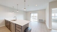 Located at 5504 Tremont Ave in Davenport, Iowa, this one-bedroom, one-bathroom unit offers a thoughtfully designed layout with modern finishes throughout. The open-concept kitchen and living area serves as the heart of the home, featuring light wood-style flooring, recessed lighting, and stylish pendant lights above a generous kitchen island with a white quartz countertop and undermount sink. Dark-toned cabinetry with brushed nickel hardware complements the full suite of stainless steel appliances, including a refrigerator, microwave, and range. A sliding glass door in the living area opens to a private balcony, flooding the space with natural light and providing outdoor views. The bedroom is carpeted for comfort, features a large window with outdoor views, a ceiling fan, and access to two closets. The bathroom is well-appointed with a wide dark wood vanity, white quartz countertop, a large mirror, and bright overhead lighting. A dedicated laundry area and a hallway with additional storage add everyday convenience. The unit's neutral color palette, clean lines, and contemporary design elements create a bright, cohesive, and functional living environment.
