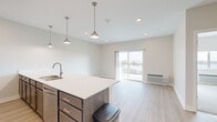 Located at 5504 Tremont Ave in Davenport, Iowa, this one-bedroom, one-bathroom unit offers a thoughtfully designed layout with modern finishes throughout. The open-concept kitchen and living area serves as the heart of the home, featuring light wood-style flooring, recessed lighting, and stylish pendant lights above a generous kitchen island with a white quartz countertop and undermount sink. Dark-toned cabinetry with brushed nickel hardware complements the full suite of stainless steel appliances, including a refrigerator, microwave, and range. A sliding glass door in the living area opens to a private balcony, flooding the space with natural light and providing outdoor views. The bedroom is carpeted for comfort, features a large window with outdoor views, a ceiling fan, and access to two closets. The bathroom is well-appointed with a wide dark wood vanity, white quartz countertop, a large mirror, and bright overhead lighting. A dedicated laundry area and a hallway with additional storage add everyday convenience. The unit's neutral color palette, clean lines, and contemporary design elements create a bright, cohesive, and functional living environment.