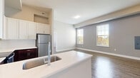 Located at 6770 Printers Blvd in New Albany, Ohio, this single-floor, 2-bedroom, 2-bathroom residence offers a thoughtfully designed layout with contemporary finishes throughout. The open-concept kitchen and living area serves as the heart of the home, featuring a large island with a white quartz countertop and undermount sink, two-tone cabinetry with crisp white upper cabinets and rich dark lower cabinets, a subway tile backsplash, and a full suite of stainless steel appliances. Wood-look flooring flows through the main living and kitchen areas, while large windows invite abundant natural light and outdoor views into the living room. Both bedrooms are generously sized and finished with plush carpeting and natural light from well-positioned windows. Each bedroom is paired with its own closet, including a walk-in closet with wire shelving for organized storage. The two bathrooms are finished with clean white vanities and wood-look flooring. One features a tub-shower combo, while the other offers a sleek glass-enclosed walk-in shower. Neutral gray tones, white trim, and consistent modern fixtures create a cohesive and welcoming ambiance throughout the entire residence.