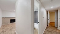 This single-story, 2-bedroom, 2-bathroom residence in Austin, TX offers a well-organized layout with modern finishes throughout. Light wood-look flooring flows consistently across the living areas, hallways, and bedrooms, creating a cohesive and inviting aesthetic. The spacious living room is highlighted by a striking reclaimed wood accent wall, a pendant light fixture, ceiling fan, and recessed lighting, giving the space a warm yet contemporary character. An adjacent hallway connects the main living areas to the private quarters. The galley-style kitchen is outfitted with two-tone cabinetry featuring matte black hardware, white countertops, and stainless steel appliances including a refrigerator, electric range, and built-in microwave. Both bedrooms are comfortably sized, each featuring ceiling fans and closets with bifold doors. The primary bedroom includes a window that invites natural light. The two bathrooms are finished with large-format gray tile surrounding the tub-shower combinations, matte black fixtures, and warm wood-look flooring. Additional features include three closets for generous storage, two hallways connecting the layout efficiently, and a private patio for outdoor enjoyment. This residence is a well-appointed home in the heart of Austin.