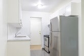 Located at 407 Sidney St, Unit 7 in Quinte West, Ontario, this 2-bedroom, 1-bathroom unit offers a practical and well-appointed single-floor layout. Light wood laminate flooring flows consistently throughout the living spaces, creating a clean and cohesive look. The living room is a comfortable, open area featuring a large window and balcony door that frame lush greenery views, allowing ample natural light to fill the room. A baseboard heating system runs along the perimeter, and a textured ceiling adds a subtle architectural detail.

The galley-style kitchen is efficiently designed with white shaker-style cabinetry, marble-look countertops, a stainless steel sink, and stainless steel appliances including a refrigerator and stove. Grey tile flooring and abundant upper and lower cabinet storage make this a highly functional space.

The primary bedroom is a well-sized room with a large window overlooking outdoor greenery, baseboard heating, and a sliding closet. The second bedroom is a comfortable, neutral-toned room with its own window and natural light.

The full bathroom is finished in a clean, white palette featuring a tiled tub-and-shower surround, a white vanity with storage, and neutral tile flooring. A connecting hallway ties all rooms together efficiently, completing this move-in ready unit.