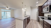 Located on Hadley Blvd in Enola, PA, this 2-bedroom, 1-bathroom residence offers a thoughtfully designed single-floor layout with modern finishes throughout. The open-concept kitchen and living area serves as the heart of the home, anchored by a central island featuring granite countertops, a stainless steel undermount sink, and elegant pendant lighting. Rich dark-espresso cabinetry lines the kitchen walls, complemented by a full suite of stainless steel appliances including a refrigerator, electric range, microwave, and dishwasher. Light wood-tone luxury vinyl plank flooring runs throughout the main living areas, adding warmth and cohesion to the space. The living room is bright and airy, with a ceiling fan and a large sliding glass door that floods the room with natural light and provides outdoor access. The spacious primary bedroom features plush carpeting, a ceiling fan, and a window with exterior views, creating a comfortable retreat. The second bedroom also offers wood-style flooring and ample natural light. The full bathroom maintains the design continuity with a granite-topped dark vanity, a large mirror, and wood-look tile flooring. A dedicated closet provides additional storage, completing this clean and contemporary residence.