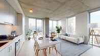 Located in the heart of Portland, Oregon, this contemporary residence showcases a striking industrial-modern aesthetic defined by exposed concrete ceilings and structural columns throughout. The open-concept living and dining area is anchored by expansive floor-to-ceiling windows on multiple walls, flooding the space with natural light and framing panoramic views of the Willamette River, the Portland cityscape, and the surrounding hills. Light hardwood flooring runs throughout, complementing the raw concrete overhead and creating a warm contrast against the minimalist palette.

The kitchen is sleekly designed with full-height cabinetry in a soft light wood finish, under-cabinet lighting, and an integrated layout that flows seamlessly into the dining area. The bedroom continues the window-forward design philosophy, offering equally impressive river and city views through large floor-to-ceiling glazing, with space for a dedicated sitting area. A dedicated walk-in closet provides organized storage off the bedroom corridor. The bathroom features earthy tile flooring, a light wood vanity with ample cabinetry, a glass-enclosed shower, and elegant pendant lighting above a wide mirror, completing the refined, cohesive character of this urban residence.