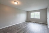 This single-floor unit offers a clean, functional layout with a cohesive design throughout. Wood-look laminate flooring flows continuously across all rooms, providing a warm and consistent aesthetic. The living area is generously sized and filled with natural light from a large window with blinds, creating an open and airy atmosphere. A textured ceiling adds a classic finishing detail to the space.

The kitchen is efficiently designed, featuring white upper and lower cabinetry, a double-basin stainless steel sink with a brushed gold faucet, a full-size refrigerator, and a dishwasher. The layout allows for easy movement and connects directly to a hallway leading to the rest of the unit.

The bedrooms are well-proportioned, each with neutral-toned walls, wood-look flooring, and windows that invite natural light. Closet access is available within the bedroom areas. A central hallway links the kitchen, bedrooms, and bathroom, providing a logical and efficient flow through the unit.

The bathroom is complete with a single-sink vanity topped with a speckled countertop, a mirrored medicine cabinet, and a shower-tub combination with a clean white surround. Overall, the space presents a tidy, move-in ready environment with practical finishes throughout.