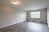 This single-floor unit offers a clean, functional layout with a cohesive design throughout. Wood-look laminate flooring flows continuously across all rooms, providing a warm and consistent aesthetic. The living area is generously sized and filled with natural light from a large window with blinds, creating an open and airy atmosphere. A textured ceiling adds a classic finishing detail to the space.

The kitchen is efficiently designed, featuring white upper and lower cabinetry, a double-basin stainless steel sink with a brushed gold faucet, a full-size refrigerator, and a dishwasher. The layout allows for easy movement and connects directly to a hallway leading to the rest of the unit.

The bedrooms are well-proportioned, each with neutral-toned walls, wood-look flooring, and windows that invite natural light. Closet access is available within the bedroom areas. A central hallway links the kitchen, bedrooms, and bathroom, providing a logical and efficient flow through the unit.

The bathroom is complete with a single-sink vanity topped with a speckled countertop, a mirrored medicine cabinet, and a shower-tub combination with a clean white surround. Overall, the space presents a tidy, move-in ready environment with practical finishes throughout.