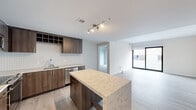 This thoughtfully designed 3-bedroom, 3-bathroom residence offers a clean, modern aesthetic across a single floor. The open-concept kitchen serves as the heart of the home, featuring rich dark wood cabinetry, a striking herringbone-patterned tile backsplash, stainless steel appliances including a gas range and built-in microwave, and a generously sized island topped with elegant marble-look quartz countertops. Light wood-style flooring flows throughout the common areas, complementing the bright, neutral palette. The living room is bathed in natural light through large sliding glass doors that frame views of the surrounding building exterior. The three bedrooms are well-proportioned, with the primary bedroom offering a comfortable footprint, plush carpeting, and access to a closet. Additional bedrooms also feature carpet flooring and large sliding glass doors or windows providing ample natural light. Two closets offer practical storage solutions. The three bathrooms are finished to a high standard, featuring large-format porcelain tile, modern floating vanities with warm wood accents and brass hardware, a soaking tub with a tiled surround in one bathroom, and a sleek glass-enclosed walk-in shower with full-height tile in another. The overall ambiance is contemporary, clean, and move-in ready.