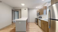 Located at 1325 South Washtenaw Avenue in Chicago's vibrant 60608 corridor, this two-bedroom, one-bathroom residence offers a well-organized, single-floor layout finished with clean, contemporary design throughout. Light wood-tone flooring runs continuously across all rooms, creating a cohesive and airy feel.

The kitchen is a standout feature, equipped with stainless steel appliances including a gas range, microwave, and dishwasher. Warm wood cabinetry pairs with a white quartz countertop and a central kitchen island, providing ample prep and storage space. A herringbone tile backsplash adds a subtle design accent.

A central hallway connects the main living spaces, with a dedicated closet providing convenient storage. The open living area benefits from large, black-framed windows that invite generous natural light and offer views of the surrounding neighborhood greenery.

The primary bedroom is a well-proportioned space featuring a large window with park views, while the second bedroom also includes a bright window overlooking tree-lined street scenery. The primary bedroom is served by a dedicated closet with built-in hanging storage.

The bathroom is finished with a wood-vanity cabinet, a white countertop sink, a large mirror, and light wood flooring, maintaining the unit's consistent modern aesthetic throughout.