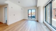 Located at 801 Orange Drive in Wilmington, Delaware, this modern 2-bedroom, 1-bathroom unit offers a thoughtfully designed single-floor layout with clean contemporary finishes throughout. Light wood-tone flooring flows consistently across the living areas and bedrooms, complementing the crisp white walls and creating a bright, cohesive aesthetic.

The open kitchen is a standout feature, equipped with sleek grey flat-front cabinetry extending to the ceiling for ample storage, white quartz countertops, a stainless steel sink, and a full suite of stainless steel appliances including a range, microwave, dishwasher, and refrigerator. Recessed lighting enhances the functional workspace.

The combined living area connects naturally to the kitchen, with large black-framed windows allowing generous natural light and urban views of the surrounding Wilmington streetscape. Both bedrooms continue the light flooring and white walls, each featuring oversized black-framed windows that bring in abundant daylight. Architectural column details add a distinctive modern touch to the layout.

The bathroom is well-appointed with large-format grey tile flooring, a wood-toned vanity with a white countertop, a sleek rectangular mirror with modern lighting, and a tall narrow window providing natural light and ventilation. The overall design is clean, modern, and move-in ready.