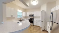 This three-story home at Cooper Creek is thoughtfully designed across multiple levels, offering a functional and comfortable layout. The kitchen serves as a standout feature, outfitted with crisp white cabinetry, light quartz countertops, and a full suite of stainless steel appliances including an electric range, built-in microwave, and dishwasher. A curved breakfast bar provides additional counter space and casual seating, while a window above the sink brings in natural light and views of surrounding greenery. Hardwood-style flooring runs through the kitchen and main living areas, lending a clean, cohesive look.

The entry level features wood-look flooring, neutral walls, and easy access to stairways connecting all three floors. Bedrooms are carpeted for comfort and include ceiling fans, windows with views of the outdoors, and generous closet space. Walk-in closets feature wire shelving systems, maximizing storage capacity. Bathrooms are finished with white vanity cabinetry, well-lit mirrors, and a shower enclosure with sliding glass doors. Throughout, the home maintains a neutral color palette, clean lines, and consistent finishes that create a bright, welcoming ambiance.