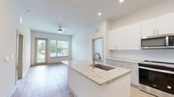 Located at 7311 Baymeadows Way in Jacksonville, FL, this well-appointed one-bedroom, one-bathroom residence offers a thoughtfully designed single-story layout with an abundance of functional living spaces. Light-toned wood-style flooring flows throughout, complementing the clean, neutral palette of the interiors.

The open-concept kitchen, dining, and living area serves as the heart of the home. The kitchen is outfitted with crisp white cabinetry, a white subway tile backsplash, granite countertops, a center island for additional prep space, and a full suite of stainless steel appliances including a refrigerator with ice maker, range, dishwasher, and microwave. A ceiling fan overhead and large windows allow natural light to fill the adjoining living area, which opens directly to a private patio overlooking a landscaped courtyard framed by palm trees.

The bedroom is a comfortable, well-sized retreat with a window offering outdoor views and a ceiling fan. Generous storage is provided through four closets, including a walk-in fitted with wire shelving. A versatile den provides additional flexible living space.

The bathroom features a granite-topped vanity with undermount sink, a tiled shower-tub combination, and wood-style flooring. A dedicated laundry area adds everyday convenience to complete this functional and modern residence.