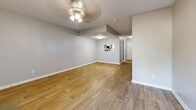 Located at 8623 Starcrest Dr. in San Antonio, TX, this two-story home offers a thoughtful layout spread across two well-proportioned floors. The main level features a welcoming living room with warm wood-look vinyl flooring, a ceiling fan, and a charming brick fireplace as the focal point, flanked by two white-paneled doors. A pass-through window connects the living area to the hallway, enhancing the open feel of the space. The lower level also includes easy access to the staircase, which features a classic white-spindle railing. Upstairs, the generously sized primary bedroom is carpeted for comfort and includes a ceiling fan and a window that brings in natural light. An adjacent bathroom is appointed with dark wood cabinetry, granite countertops, and wood-look tile flooring, with a dedicated walk-in closet featuring built-in shelving and hanging rods. The home includes a total of three bathrooms, one of which features a tub/shower combination and a bright window. Additional highlights include a private balcony overlooking the surrounding neighborhood with mature trees, a dedicated walk-in closet, and a neutral gray and white interior palette throughout that lends a clean, move-in-ready aesthetic.