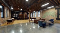 Located at 1352 N Wells St in Chicago's vibrant Old Town neighborhood, this single-floor space combines industrial architecture with an energetic, urban aesthetic. The design is anchored by exposed brick walls, original heavy timber columns and ceiling beams, and polished concrete floors that transition into warm hardwood in select zones, creating a dynamic contrast throughout.

The main gathering area is generously open, accommodating lounge seating with leather sofas and club chairs arranged around a low-profile coffee table. Bold, colorful graffiti-style murals cover the brick walls, adding a distinctly creative and artistic character to the space. A wall-mounted flat-screen television enhances the lounge area for viewing and entertainment.

A dedicated game zone features a regulation pool table and a shuffleboard table, complemented by bar-height seating and framed photography displayed against dark-painted accent walls. A vintage arcade cabinet adds a playful retro touch. A separate dining area with dark wood tables and upholstered chairs provides a more intimate setting.

The entrance lobby impresses with soaring ceilings, expansive floor-to-ceiling glazing that floods the space with natural light, exposed ductwork, and a reception desk framed by red steel accents and brick. The overall ambiance is lively, creative, and well-suited for private events, gatherings, or social activities.