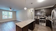 This single-floor residence offers a thoughtfully designed layout across two bedrooms and two bathrooms. The open-concept kitchen is a standout feature, showcasing dark espresso cabinetry reaching toward the ceiling, a striking multi-tone tile backsplash, stainless steel appliances including a gas range, dishwasher, and refrigerator, and a granite-topped island with pendant lighting overhead. The kitchen flows naturally into the living area, which features wood-look flooring and a ceiling fan.

The spacious primary bedroom is finished with plush carpet, a ceiling fan, and a natural light-filled window. It connects directly to a full bathroom with white subway tile surrounding the tub-shower combo, tile flooring, and a dark-cabineted vanity, as well as a walk-in closet equipped with wire shelving. The second bedroom mirrors this comfort with wood-look flooring, a ceiling fan, and its own window view. A second full bathroom with matching finishes serves this room. Additional features include a dedicated laundry area with wire shelving and water heater access, and two closets providing ample storage throughout the home.
