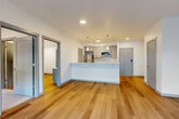 Located at 2707 E 6th St in Vancouver, WA, this well-designed one-bedroom, one-bathroom unit offers a thoughtfully arranged single-floor layout with a clean, contemporary aesthetic. The open-concept kitchen and living area serves as the heart of the unit, featuring gray shaker-style cabinetry, white quartz countertops with a subway tile backsplash, and a full suite of stainless steel appliances including a refrigerator, range, microwave, and dishwasher. A peninsula with pendant lighting above provides both additional prep space and a natural visual divide between the kitchen and the living area. The living room receives generous natural light through large floor-to-ceiling windows, offering outdoor views and a bright, airy atmosphere. Warm-toned hardwood-style flooring flows throughout the main living spaces, complementing the unit's neutral color palette. The bedroom is a comfortable, carpet-floored retreat with a window fitted with a roller shade for privacy and light control. A dedicated walk-in closet offers convenient storage with built-in rod shelving. The unit also features recessed and pendant lighting throughout, a wall-mounted climate control unit, and modern gray door and trim accents that tie the space together with a cohesive, contemporary finish.