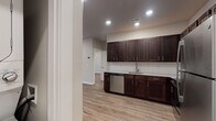 Located on E Township St in Fayetteville, Arkansas, this single-floor unit offers a clean, modern aesthetic with consistent wood-look flooring and neutral tones carried throughout every room. The kitchen is a standout feature, showcasing rich dark-walnut shaker-style cabinetry extending to the ceiling for ample storage, light granite countertops, a stainless steel undermount sink, and a full suite of stainless steel appliances including a refrigerator, range, microwave, and dishwasher. Recessed lighting illuminates the space efficiently. The open-concept living and dining area is generously proportioned, with natural light filtering in through slatted blinds and recessed ceiling lights enhancing the bright, airy atmosphere. The bedroom features a ceiling fan, a well-sized window for natural light, and direct access to a walk-in closet. The bathroom continues the design language of the kitchen, with matching dark cabinetry, granite countertops, and a undermount sink paired with brushed nickel fixtures. The overall layout is thoughtfully organized, connecting the living, kitchen, bedroom, and bathroom areas with clean hallways and crisp white door trim, creating a cohesive and move-in-ready living environment.