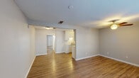This one-bedroom, one-bathroom flat in Lafayette, Louisiana offers a practical and well-organized single-story layout. The open living area features warm hardwood-style flooring, neutral gray walls, and a ceiling fan with light fixture, creating a bright and comfortable atmosphere. Two large windows allow natural light to fill the space, adding to its airy feel. The galley-style kitchen is efficiently designed with white cabinetry, ample upper and lower storage, a double-basin sink, laminate countertops, and white appliances including a refrigerator and electric range. A pass-through opening connects the kitchen to the main living area, enhancing the sense of openness. The bedroom is carpeted for added comfort and features a ceiling fan, a window with blinds, and notably, two side-by-side reach-in closets providing generous storage. The full bathroom includes a single-sink vanity with a speckled countertop, a wall-mounted mirror with overhead lighting, and a tub-shower combination. A textured ceiling is consistent throughout the unit. The entry area is carpeted and includes a paneled front door with an adjacent window, completing this clean and functional floor plan.