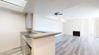 Located in the heart of Hollywood at 1335 N La Brea Ave, this 2-bedroom, 2-bathroom residence offers a well-designed single-floor layout with modern finishes throughout. Light gray wood-look flooring runs seamlessly across the entire unit, creating a cohesive and contemporary aesthetic.

The open-concept living area is bright and airy, anchored by a classic fireplace and ceiling fan, with large sliding glass doors that lead to a private balcony and fill the space with natural light. The kitchen is outfitted with gray shaker-style cabinetry, granite countertops, stainless steel appliances including a gas range and refrigerator, and a peninsula that opens to the living area — ideal for both daily use and entertaining.

Both bedrooms are generously sized, featuring large windows with vertical blinds that allow ample natural light. The primary bedroom offers a comfortable retreat with its own dedicated closet. In total, four closets are distributed throughout the unit, providing exceptional storage.

Each bathroom features granite-topped vanities with gray cabinetry, tub-shower combinations with sliding glass enclosures, and wood-look flooring. The clean, neutral palette across both bathrooms reinforces the home's cohesive modern style. The unit's layout is thoughtfully organized to maximize functionality across every room.
