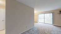 Located at 4548 Warrensville Center Rd in North Randall, Ohio, this single-floor unit offers a clean, functional layout designed for comfortable everyday living. The spacious living area is finished with neutral-toned wall-to-wall carpeting and features a large sliding glass door fitted with vertical blinds, allowing generous natural light to fill the room while providing outdoor views. A pendant light fixture adds a focal point to the dining area, and baseboard heating runs throughout the unit for consistent warmth. The entry foyer provides a welcoming transition into the living space, with a closet conveniently located near the front door. The bedrooms are well-proportioned, each featuring plush carpeting, vertical-blind windows that bring in natural light, and baseboard heating units. One bedroom also includes a wall-mounted air conditioning unit for added climate control. The bathroom is finished in classic white tile, featuring a full tub-shower combination, a white vanity with an integrated sink, a medicine cabinet with mirror, and mosaic tile flooring. The neutral color palette and clean finishes throughout create a bright, move-in-ready atmosphere suited for a range of lifestyles.