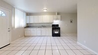 Located at 819 W 137th St in Compton, CA, this single-story, 2-bedroom, 1-bathroom home offers a functional and straightforward layout across one level. The open-concept living, dining, and kitchen area forms the heart of the home, creating a connected and accessible common space. The kitchen is equipped with ample white cabinetry extending from floor to ceiling, grey laminate countertops, a stainless steel double sink, and a black gas range with an overhead ventilation hood. White tile flooring runs throughout, lending a clean, cohesive look to the entire home. Both bedrooms are bright and simply appointed, featuring large windows with vertical blinds that invite natural light, neutral grey walls, and warm-toned tile flooring. The primary bedroom includes a mirrored sliding-door closet with built-in shelving and hanging rods, providing practical storage. The second bedroom also offers a dedicated closet. The bathroom is efficiently designed, featuring white tile flooring, a tub-shower combination, a pedestal-style vanity with a mirror cabinet, and overhead lighting. Additional utility space and two closets round out the home's practical storage offerings.