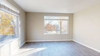 Located at 255 W Broadway in Eugene, Oregon, this two-bedroom, one-bathroom unit offers a well-designed single-floor layout. The open living area is bathed in natural light, courtesy of large windows on two walls that frame views of surrounding trees, creating a bright and welcoming atmosphere. Light-toned hardwood-style flooring runs throughout the main living spaces, complementing the neutral warm-gray walls.

The galley-style kitchen is efficiently arranged, featuring stainless steel appliances including a refrigerator, range, and dishwasher, alongside white cabinetry with brushed metal hardware and dark countertops. A ceiling fan and track lighting provide functional illumination, while a window at the end of the kitchen allows additional natural light.

The primary bedroom is generously sized, boasting two large windows that offer abundant daylight and leafy outdoor views. The second bedroom features soft carpeting and a window that fills the room with natural light. Both bedrooms are well-proportioned and versatile in layout.

The bathroom includes a vanity with white cabinetry, dark countertop, a large mirror with overhead lighting, and hardwood-style flooring that carries a warm tone. Clean, modern finishes throughout maintain a cohesive and practical aesthetic across the entire unit.