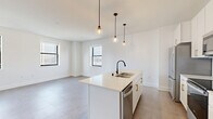 Located at 758 North Broadway in Milwaukee, WI, this thoughtfully designed 2-bedroom, 2-bathroom unit offers a clean, modern aesthetic across a single floor. The open-concept kitchen and living area serves as the heart of the home, anchored by a central island with a sleek matte black faucet, white quartz countertops, white cabinetry with gold hardware, and stainless steel appliances. Stylish pendant lights hang above the island, adding warmth to the bright, tile-floored space. Multiple windows flood the living area with natural light and frame views of the Milwaukee skyline. The two bedrooms feature plush carpeting and large windows that capture city views, with three closets providing ample storage. A dedicated laundry area adds everyday convenience. The two bathrooms are finished with classic black-and-white hexagonal tile flooring. One bathroom features a walk-in glass-enclosed shower with white subway tile, while the other offers a full tub-shower combo with matching tile surround and a white vanity. A hallway with large-format tile connects the living spaces to the private quarters, maintaining a cohesive, contemporary feel throughout the unit.