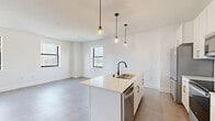Located at 758 North Broadway in Milwaukee, WI, this thoughtfully designed 2-bedroom, 2-bathroom unit offers a clean, modern aesthetic across a single floor. The open-concept kitchen and living area serves as the heart of the home, anchored by a central island with a sleek matte black faucet, white quartz countertops, white cabinetry with gold hardware, and stainless steel appliances. Stylish pendant lights hang above the island, adding warmth to the bright, tile-floored space. Multiple windows flood the living area with natural light and frame views of the Milwaukee skyline. The two bedrooms feature plush carpeting and large windows that capture city views, with three closets providing ample storage. A dedicated laundry area adds everyday convenience. The two bathrooms are finished with classic black-and-white hexagonal tile flooring. One bathroom features a walk-in glass-enclosed shower with white subway tile, while the other offers a full tub-shower combo with matching tile surround and a white vanity. A hallway with large-format tile connects the living spaces to the private quarters, maintaining a cohesive, contemporary feel throughout the unit.
