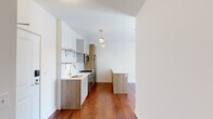 Located at 1107 W Lawrence Ave in Chicago's vibrant Uptown neighborhood, this single-floor unit showcases a thoughtfully designed interior with modern finishes throughout. Rich hardwood flooring flows continuously across the living areas, anchoring the space with warmth and visual cohesion.

The kitchen serves as a central highlight, featuring light wood cabinetry paired with white upper cabinets and open shelving against a classic white subway tile backsplash. Stainless steel appliances include a gas range, built-in microwave, refrigerator, and dishwasher. A peninsula with a white quartz countertop extends the workspace and provides a natural division between the kitchen and living area. Pendant lighting with a brushed brass finish adds an inviting ambiance overhead.

The bathroom is finished with a navy vanity topped with a white quartz surface, a frameless glass walk-in shower with vertical white tile, and polished stone-look floor tile, creating a clean, contemporary aesthetic.

A generously sized walk-in closet features multiple shelving tiers and hardwood flooring, offering substantial storage capacity. The open floor plan and crisp white walls throughout contribute to a bright, airy feel well-suited for comfortable urban living.
