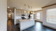 Located at 4113 Simcoe Ln in Louisville, Kentucky, this single-floor home offers a thoughtfully designed layout with modern finishes throughout. The open-concept kitchen serves as a centerpiece, showcasing gray shaker-style cabinetry, white quartz countertops, and a classic subway tile backsplash. A central island with an undermount sink provides additional workspace, while stainless steel appliances—including a French door refrigerator, electric range, over-the-range microwave, and a built-in wine cooler—complete the well-equipped space. Elegant pendant lighting and a decorative lattice detail add character, and dark hardwood-style flooring ties the kitchen and adjoining dining area together seamlessly. Natural light flows in through multiple windows fitted with horizontal blinds. The bedrooms feature neutral-toned carpet and generous windows that bring in outdoor views. The primary bathroom is notably spacious, offering an extended dual-sink vanity with ample cabinetry, wood-look tile flooring, a large framed mirror, and direct access to a walk-in closet. A secondary bathroom features marble-look tiled tub and shower surround with brushed nickel fixtures. Throughout, the home maintains a clean, contemporary palette with five-panel doors and crisp white walls.