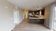 Located at 6137 Telluride Way in Denver, Colorado, this single-floor residence showcases a clean, contemporary design throughout. The open-concept kitchen is a standout feature, outfitted with rich dark wood cabinetry, sleek light quartz countertops, a herringbone-patterned tile backsplash, and a full suite of stainless steel appliances including a refrigerator with ice maker, range, microwave, and dishwasher. A spacious kitchen island provides additional prep and seating space, while pendant lighting and a track lighting system illuminate the area with style. Light wood-tone luxury vinyl plank flooring flows through the main living and kitchen areas, lending warmth and continuity to the space. The living area is open and versatile, seamlessly connecting to the kitchen and hallway. Bedrooms feature plush carpeting, neutral wall tones, and windows with blinds that bring in natural light and outdoor views. One bedroom includes a ceiling fan for added comfort. The bathrooms are finished with matching dark wood vanities, light quartz countertops, tile flooring, and framed mirrors, maintaining the cohesive modern aesthetic found throughout the home. The overall design is characterized by neutral tones, modern fixtures, and a well-considered layout that balances functionality with contemporary style.