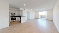 This thoughtfully designed single-floor unit offers a clean, contemporary aesthetic throughout, with light wood-style flooring and crisp white walls creating a bright and cohesive atmosphere. The open-concept layout connects the kitchen and living area seamlessly, allowing for flexible use of the generous shared space. Large sliding glass doors in the living area lead to a private balcony, filling the interior with abundant natural light and offering outdoor views of the surrounding neighborhood.

The kitchen is well-appointed with white shaker-style cabinetry, dark countertops, and a full suite of stainless steel appliances including a refrigerator, gas range, microwave, and dishwasher. A peninsula provides additional counter space and reinforces the open flow of the main living area.

The bedrooms feature light flooring, recessed lighting, and floor-to-ceiling mirrored sliding closet doors that enhance the sense of space. Natural light enters through well-placed windows with neighborhood views. 

The bathroom is finished in a clean, modern style with light wood-look flooring, a grey vanity with white countertop, a large mirror, and a tub and shower combination enclosed by sliding glass doors. The overall design of the unit is functional, bright, and move-in ready.