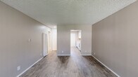 This single-story 2-bedroom, 1-bathroom unit offers a practical and comfortable layout designed to maximize functionality. The living room serves as the heart of the home, featuring wood-look laminate flooring, warm neutral-toned walls, and a textured ceiling. A window unit provides climate control, and a large window allows natural light to filter in with views of the surrounding greenery. The kitchen is bright and clean, outfitted with white cabinetry, white appliances, and a classic tile backsplash, accessible directly from the living area. A connecting hallway leads to the rest of the unit, maintaining a smooth flow between spaces. The generously sized primary bedroom is carpeted for comfort and includes a sliding mirrored closet for storage, along with a folding door that connects to an adjacent space. The second bedroom also features carpet flooring and a window with vertical blinds that brings in natural light. The bathroom is clean and efficiently designed, featuring a full tub-shower combo with white tile surround, a vanity with storage, and a medicine cabinet mirror. Throughout the unit, white baseboards and a consistent neutral palette create a cohesive, move-in ready environment.