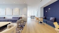 Located at 108 Eastdale Ave in Toronto's East End, this beautifully designed Party & Games Room serves as a sophisticated amenity space ideal for entertaining and recreation. The single-floor layout is generously proportioned, offering a seamless flow between two distinct yet connected zones. Light oak hardwood flooring runs throughout, complemented by crisp white walls and recessed lighting that create a bright, airy atmosphere.

The games area is anchored by a full-size pool table beneath a striking modern pendant light fixture, alongside a ping-pong table positioned near floor-to-ceiling sheer curtains that allow abundant natural light to filter in. A bold abstract canvas artwork adds a vibrant focal point to this zone.

The lounge area transitions smoothly from the games space, featuring a large sectional sofa in muted purple-grey tones, a marble-top coffee table, and a curated mix of cane-back chairs and contemporary accent seating. A sleek wall-mounted fireplace with a marble surround and a flat-screen TV above anchors this side of the room. An intimate nook with navy upholstered seating provides a quieter retreat within the space. Tasteful artwork and textured wall panels complete the refined, modern aesthetic throughout.