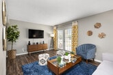This 2-bedroom, 2-bathroom single-story residence offers a thoughtfully designed layout across a comfortable footprint. The living room serves as the heart of the home, featuring wood-style flooring, a textured ceiling, and a set of French doors that open to a private patio, filling the space with natural light. The dining area connects seamlessly to the living space, accented by a warm yellow feature wall and wood-style flooring that flows throughout the common areas. The kitchen is well-equipped with white shaker cabinetry, granite-style countertops, stainless steel appliances including a refrigerator, range, microwave, and dishwasher, and conveniently houses a full-size in-unit washer and dryer. The primary bedroom is generously sized, carpeted for comfort, and features soft blue walls, a window with natural light, and ample closet space. The second bedroom also offers carpeting, a closet, and neutral tones. Both bathrooms are finished with white shaker vanities and granite-style countertops. A connecting hallway ties the private and shared spaces together, creating a functional and cohesive floor plan throughout the home.