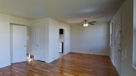 Located at 111 Wayne Road in Bridgeton, New Jersey, this two-story home offers a straightforward and functional layout designed for comfortable everyday living. The main living area is bright and open, showcasing warm hardwood flooring that runs throughout and provides a classic, timeless aesthetic. A ceiling fan with a built-in light fixture anchors the living space, offering both comfort and ambient lighting. Neutral white walls keep the interior feeling clean and airy, while floor-level vents suggest a central heating and cooling system for year-round comfort. A dedicated laundry area is conveniently tucked within the home, visible through a doorway off the main living space, complete with stacked washer and dryer units — a practical amenity for everyday use. An additional door provides access to a separate room or storage area, adding versatility to the floor plan. The home's two-story structure allows for a natural separation between living and sleeping areas. Overall, the space presents a well-maintained interior with functional features, hardwood floors, and a clean, move-in-ready condition that suits a variety of lifestyles.
