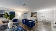 This thoughtfully designed 2-bedroom, 2-bathroom single-floor home offers a comfortable and functional layout across a generous footprint. The open-concept living, dining, and kitchen area forms the heart of the home, finished with rich wood-look flooring throughout. The spacious living room features a textured ceiling, chair-rail molding along the walls, and a ceiling fan, creating a welcoming atmosphere with ample room for relaxing and entertaining. Large windows allow natural light to fill the space. The dining area is defined by a pendant light overhead and seamlessly connects to the kitchen, which features a galley-style layout with gray cabinetry, a tile backsplash, black appliances including a range and refrigerator, and light stone countertops. Both bedrooms are carpeted and well-sized, with windows that provide natural light and outdoor views. The primary bedroom offers a generous footprint, while each bedroom is served by its own full bathroom. The bathrooms feature wood-look flooring, vanities with stone-look countertops, and tub-shower combinations. Additional highlights include two closets, two hallways for efficient circulation, and a dedicated in-unit laundry room with washer and dryer hookups and overhead shelving for added storage.