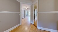 Located at 803 E State St in Milwaukee's vibrant East Side neighborhood, this single-floor residence offers a well-organized layout across a comfortable footprint. Warm hardwood floors run throughout the entire space, tying together each room with a cohesive, classic aesthetic. The entrance welcomes visitors with charming mosaic tile flooring and a rich, dark wood door framed by ornate white millwork. Adjacent to the entry, a living room features a decorative fireplace with built-in shelving — a standout architectural detail adding character and warmth. A ceiling fan and a bay window allow natural light to fill the room while offering views of the street. The hallways connect the living areas smoothly to two well-proportioned bedrooms, each with hardwood floors and white panel doors with period-appropriate hardware. The kitchen is equipped with warm oak cabinetry, subway tile backsplash, a gas range, and direct exterior access, offering both function and natural light. A dedicated laundry room houses a stacked washer and dryer unit for added convenience. Additional spaces include a family room, dining room, and a bonus room, providing flexible use throughout. Crown molding and white trim details are consistent across rooms, reinforcing the home's traditional character.