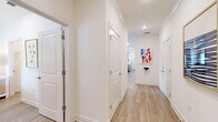 This single-floor home offers a bright and well-organized layout across two bedrooms, two bathrooms, and a combined kitchen and living area. The living room is a vibrant, welcoming space characterized by large windows dressed with bold, colorful patterned curtains that flood the room with natural light. Light wood-tone flooring runs throughout, complementing the warm, eclectic decor. A ceiling fan anchors the room, while ample space accommodates both relaxed seating and accent furniture. The kitchen is well-equipped with white shaker-style cabinetry, granite countertops, stainless steel appliances, a stainless range hood, and a central island with seating — ideal for both cooking and casual dining. Pendant lighting and a window above the sink add brightness to the space. The primary bedroom is generously sized, featuring a ceiling fan, natural light from a large window, and serene, coastal-inspired decor. The primary bathroom offers a double-sink vanity with granite countertops, light gray cabinetry, wood-look flooring, and a separate shower. The second bedroom is cozy and well-lit, sharing a similarly styled bathroom featuring a tub-shower combo and a single vanity. Two closets provide additional storage, and the attached garage offers practical utility space.