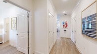 This single-floor home offers a bright and well-organized layout across two bedrooms, two bathrooms, and a combined kitchen and living area. The living room is a vibrant, welcoming space characterized by large windows dressed with bold, colorful patterned curtains that flood the room with natural light. Light wood-tone flooring runs throughout, complementing the warm, eclectic decor. A ceiling fan anchors the room, while ample space accommodates both relaxed seating and accent furniture. The kitchen is well-equipped with white shaker-style cabinetry, granite countertops, stainless steel appliances, a stainless range hood, and a central island with seating — ideal for both cooking and casual dining. Pendant lighting and a window above the sink add brightness to the space. The primary bedroom is generously sized, featuring a ceiling fan, natural light from a large window, and serene, coastal-inspired decor. The primary bathroom offers a double-sink vanity with granite countertops, light gray cabinetry, wood-look flooring, and a separate shower. The second bedroom is cozy and well-lit, sharing a similarly styled bathroom featuring a tub-shower combo and a single vanity. Two closets provide additional storage, and the attached garage offers practical utility space.