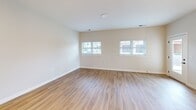 This 990-square-foot single-floor apartment offers a thoughtfully designed layout with 2 bedrooms, 2 bathrooms, and 2 closets. The open-concept kitchen and living area serves as the heart of the home, featuring warm wood-look luxury vinyl plank flooring throughout. The kitchen is equipped with white shaker-style cabinetry reaching to the ceiling, a white quartz-topped island with an undermount sink, stainless steel appliances including a refrigerator with ice maker and an electric range, white subway tile backsplash, and stylish globe pendant lighting. The living area benefits from dual windows that allow ample natural light to fill the space. Both bedrooms are carpeted and feature windows with exterior views. The primary bedroom measures 180 square feet and provides access to an en-suite bathroom equipped with a sliding glass-door walk-in shower featuring dark bronze hardware. The second bathroom is finished with matching light wood-look flooring, clean white walls, and matte black hardware accents. Throughout the unit, neutral beige tones, white trim, and consistent finishes create a cohesive, modern aesthetic well-suited for comfortable everyday living.
