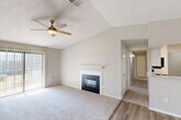 Located at 222 Kyser Blvd in Madison, Alabama, this single-floor, 2-bedroom, 2-bathroom home offers a functional and comfortable layout. The open living room immediately impresses with dramatic vaulted ceilings that lend a sense of spaciousness well beyond the floor plan's footprint. A ceiling fan with light fixture complements the room, while a classic white-mantled fireplace serves as the focal point. Light wood-style hard surface flooring transitions to plush carpeting throughout the living and bedroom areas. A sliding glass door fills the living room with natural light and provides outdoor access. The galley-style kitchen features white cabinetry, light countertops, black appliances including a refrigerator, electric range, microwave, and dishwasher, as well as wood-look flooring and a stainless steel sink. Both bedrooms are generously sized, carpeted, and equipped with ceiling fans. The primary bedroom offers ample space and dedicated closet storage. The bathrooms include tub/shower combinations with clean white tile surrounds. A dedicated laundry room with built-in shelving and washer/dryer hookups adds everyday convenience. Three closets throughout the home provide abundant storage. The neutral color palette and textured ceilings complete the cohesive, move-in-ready aesthetic.