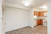 This single-floor residence offers a practical and well-organized layout across several distinct living areas. The kitchen is equipped with warm honey-toned wood cabinetry extending to the upper walls, granite-look laminate countertops, and matching white appliances including a range, over-the-range microwave, and refrigerator. Stone-look tile flooring runs throughout the kitchen, lending durability to the space.

The living area is finished with neutral wall-to-wall carpeting and features a sliding glass door that opens to a private balcony, allowing natural light to fill the room and providing views of the surrounding neighborhood. An adjacent storage closet adds functional convenience to the area.

The bedrooms continue the carpeted flooring and neutral color palette, each offering sliding or hinged closets for storage. Windows fitted with horizontal blinds allow natural light while maintaining privacy. The rooms provide a clean, open canvas suitable for varied furniture arrangements.

The full bathroom includes a single-sink vanity with granite-look countertops set into warm wood cabinetry, a toilet, and a full-size tub and shower combination with a curved chrome curtain rod. Stone-look tile flooring complements the clean, white fixtures throughout, creating a cohesive and functional space.