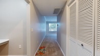 This thoughtfully designed 2-bedroom, 2-bathroom single-floor residence offers a practical and comfortable layout across a well-utilized footprint. The entrance leads into carpeted hallways with louvered closet doors and ceiling HVAC vents, setting a clean, neutral tone throughout. The living room features plush carpeting and large windows that flood the space with natural light and offer leafy outdoor views, creating an open and airy atmosphere. Crown molding adds a refined architectural detail that carries into the adjoining dining area, which boasts warm hardwood flooring, a pendant light fixture, and dual windows framing lush greenery outside. The galley-style kitchen is equipped with gray cabinetry, white countertops, black stainless appliances including a range and microwave, and hardwood flooring, with a pass-through window connecting it to the dining area. Both bathrooms feature hardwood flooring, white tile tub-shower combinations, vanities with gray cabinetry, and bright overhead lighting. The primary bedroom is generously sized with carpeting, a ceiling fan, and a large window with outdoor views. Each bedroom includes its own closet — one notably spacious walk-in closet fitted with wire shelving systems. The overall ambiance is clean, neutral, and move-in ready.