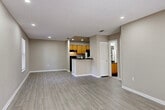 Located at 4230 Atoll Ct in Naples, Florida, this single-story unit offers a thoughtfully designed open-concept layout finished with a neutral, warm color palette throughout. The main living area is generously proportioned, featuring light wood-look flooring, recessed lighting, and a textured ceiling that extends into the adjacent dining and kitchen spaces. Large windows allow natural light to filter in, enhancing the bright and airy atmosphere.

The kitchen is designed in a galley style, equipped with warm-toned wood cabinetry, dark granite-style countertops, black appliances including a refrigerator and range, and a peninsula that opens toward the living area. A hallway connects the kitchen to additional rooms and storage areas.

The bedrooms are carpeted for comfort and each feature ceiling fans with light fixtures. One bedroom includes a walk-in closet and a sliding glass door providing access to the outdoors, while another features a standard closet. The bathroom is outfitted with wood cabinetry, a dark countertop vanity, a tub-shower combination, and tile-style flooring. Overall, the unit presents a clean, move-in ready aesthetic suitable for Naples living.