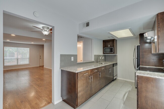 Cocina con electrodomésticos de acero inoxidable, encimeras de granito y amplio espacio de almacenamiento. - 4525 Gilbert Ave