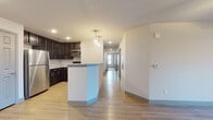 This single-floor unit offers a well-organized layout with distinct living, kitchen, and sleeping areas connected by a central corridor. The kitchen is appointed with dark espresso cabinetry, granite-look countertops, and a full suite of stainless steel appliances including a refrigerator, range, microwave, and dishwasher. A peninsula with pendant lighting separates the kitchen from the main living and entry areas, which feature light wood-look flooring throughout. The living area is open and bright, with a ceiling fan and double French doors that provide access to an outdoor patio and allow natural light to fill the space. Multiple bedrooms are finished with neutral carpet, ceiling fans, and windows fitted with blinds for privacy and light control. Each bedroom includes closet storage. The bathroom features a full tub-shower combination, a dark-cabinet vanity with a granite-look countertop, and wood-look flooring. Neutral wall tones and consistent finishes throughout create a cohesive, move-in-ready environment.