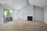 Located at 1580 Shadowridge Drive in Vista, California, this one-bedroom, one-bathroom residence offers a thoughtfully laid-out single-floor plan. The open-concept living and kitchen area serves as the heart of the home, where soaring vaulted ceilings with exposed beams create a sense of spaciousness. A wood-burning fireplace anchors the living room, complemented by plush carpeting and large windows that flood the space with natural light. Sliding glass doors lead to a private balcony overlooking lush, mature trees, extending the living area outdoors. The kitchen is well-appointed with rich wood cabinetry, granite-style countertops, a full suite of black appliances including a range, microwave, dishwasher, and refrigerator, and easy-care tile flooring. The bedroom offers a comfortable retreat with carpeted floors, a generous closet, and direct access to the full bathroom, which features a tub-shower combination and tile flooring. Multiple closets throughout provide ample storage, and a dedicated laundry area adds everyday convenience. With a neutral color palette and tree-framed views, this residence delivers a calm and functional living environment in the heart of Vista.