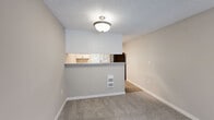 Located at 309 NE Fairgrounds Rd in Bremerton, WA, this two-bedroom, one-bathroom residence offers a well-organized single-floor layout with a clean, neutral aesthetic throughout. The combined kitchen and living area serves as the heart of the home, with a pass-through breakfast bar connecting the two spaces. The kitchen is equipped with white cabinetry, gray countertops, black appliances including an electric range and refrigerator, and wood-look flooring that adds warmth underfoot. The living room features plush carpet, a striking slate-tiled fireplace, and a sliding glass door that opens onto a private balcony with outdoor views. Both bedrooms are carpeted and receive natural light through blinded windows, with the primary bedroom offering a comfortable, well-proportioned retreat. Three closets provide ample storage throughout the unit. The bathroom features a full tub-shower combination, a white vanity with gray countertop, and wood-look flooring that mirrors the kitchen. A hallway connects the private areas of the home, and a textured ceiling is present throughout. The overall ambiance is bright, clean, and move-in ready.