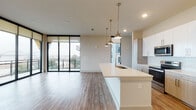 This well-appointed two-bedroom, two-bathroom residence in Memphis, Tennessee offers a thoughtfully designed single-level floor plan with a contemporary aesthetic throughout. The open-concept living and kitchen area serves as the heart of the home, anchored by a large center island with light quartz countertops and an undermount sink. Pendant lighting in brushed brass adds a warm, modern accent above the island, while white upper cabinetry, wood-toned lower cabinets, a tile backsplash, and stainless steel appliances complete the kitchen. Wood-look plank flooring runs throughout the entire residence, providing a cohesive and low-maintenance surface.

The living area opens directly to a private balcony through floor-to-ceiling black-framed sliding glass doors, offering expansive views of what appears to be the Mississippi River — a notable feature that floods the space with natural light. Both bedrooms are comfortably sized, each equipped with ceiling fans and large windows. One bedroom features direct balcony access with panoramic water views. The bathrooms include granite-topped vanities with wood-toned cabinetry, as well as a tiled tub-shower combination. A walk-in closet with wire shelving provides generous storage off the primary bath.
