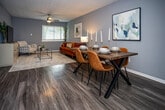 Located at 505 Buckeye Dr in Knoxville, TN, this single-floor residence offers a thoughtfully designed layout with a cohesive aesthetic defined by cool grey walls, dark hardwood-style flooring, and textured ceilings throughout. The open-concept living and dining area serves as the heart of the home, where the living space features a ceiling fan, a bright window with blinds, and generous room for seating. The adjacent dining area comfortably accommodates a full-sized table, making it well-suited for both everyday meals and entertaining. The kitchen is equipped with white cabinetry, light countertops, a stainless steel dishwasher, a double sink, and a striking mosaic tile backsplash that adds a decorative touch. The residence includes multiple bedrooms, each featuring ceiling fans, natural light from windows with blinds, and closet storage. The bedrooms share a consistent, calm color palette that promotes a restful atmosphere. The bathroom offers a vanity with a large mirror and built-in storage. A linen or storage closet with shelving provides additional organizational space. Throughout the home, the unified design choices and practical layout make this Knoxville residence a comfortable and functional living space.